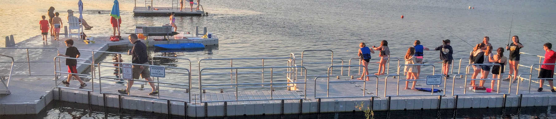Grupo de personas pescando en un muelle con barandillas