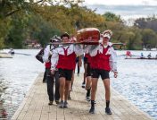A male rowing team carries their boat