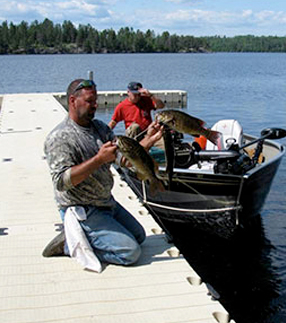 Mann som holder fisk på en brygge