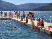 Group of people standing and swimming around floating dock
