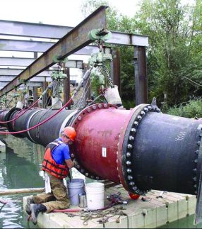 Man working on a large pipe on a floating work platform