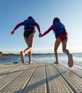 Girls holding hands to jump off dock