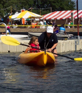 Child being guided in a kayak from a dock
