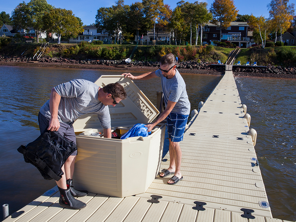 Two men pull out life vests from a dock container