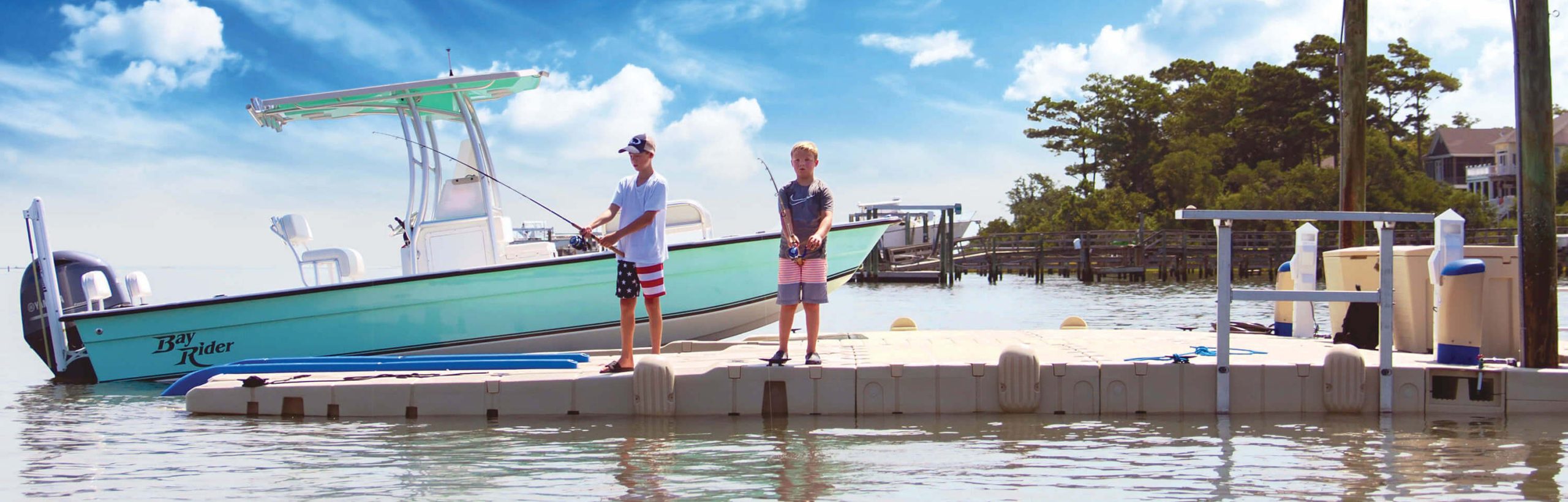 2 boys fishing on floating dock with motorboat in background