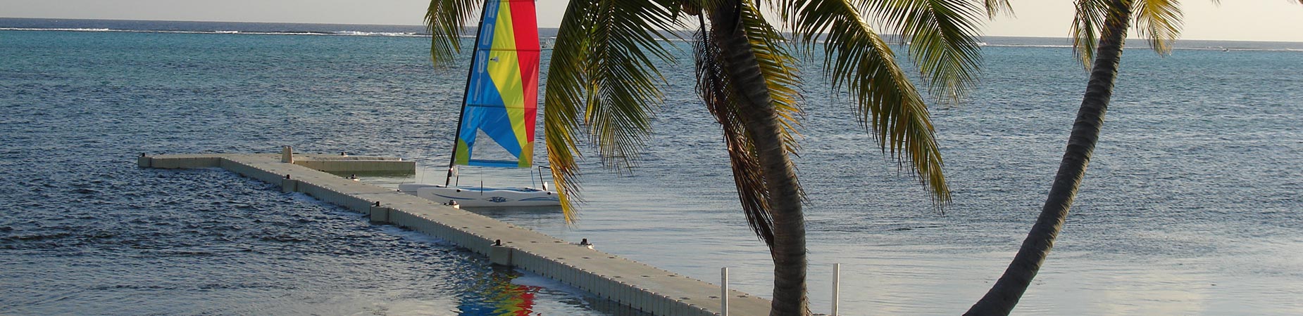View from beach of floating dock with colorful sail boat