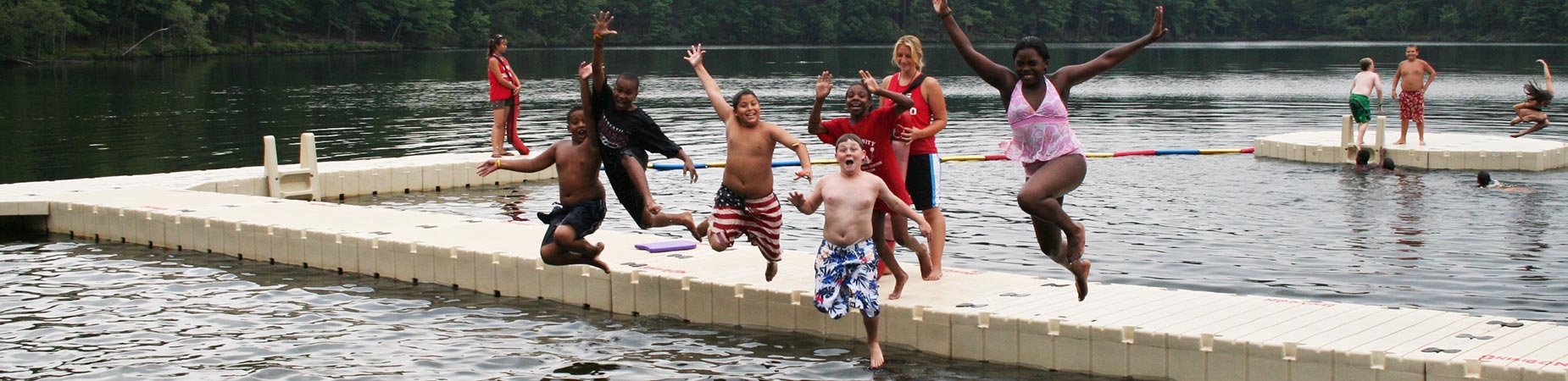 Kids jumping into water off of floating swim platform