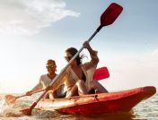 Et ungt par padler kajakk i en rød båt