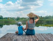 Mom and son sitting on wooden dock while fishing