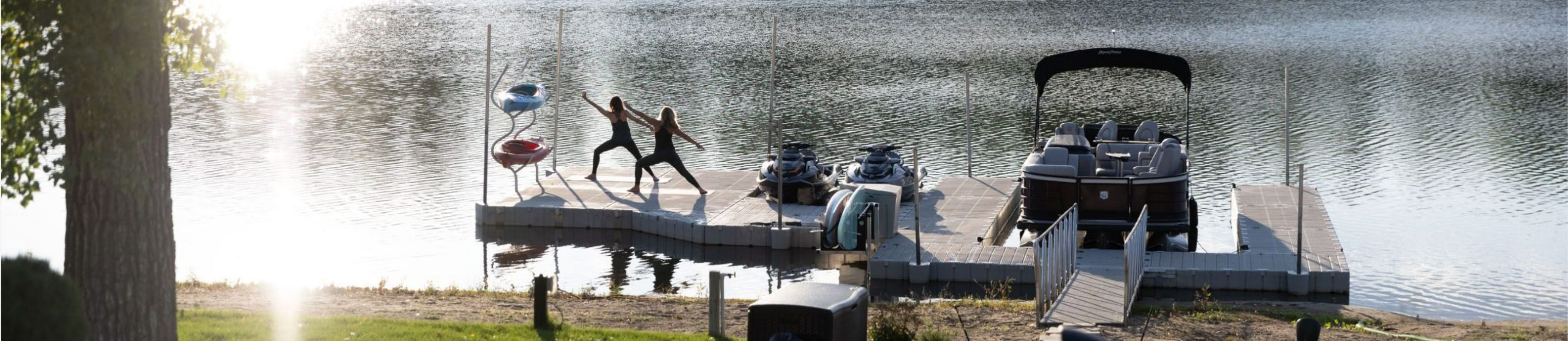2 women performing yoga on boat dock
