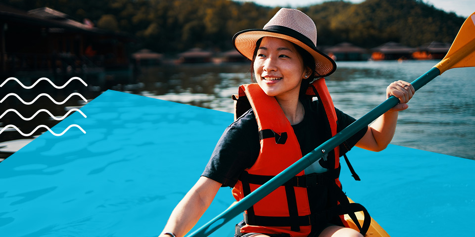 Una joven disfruta de su kayak con el chaleco salvavidas puesto