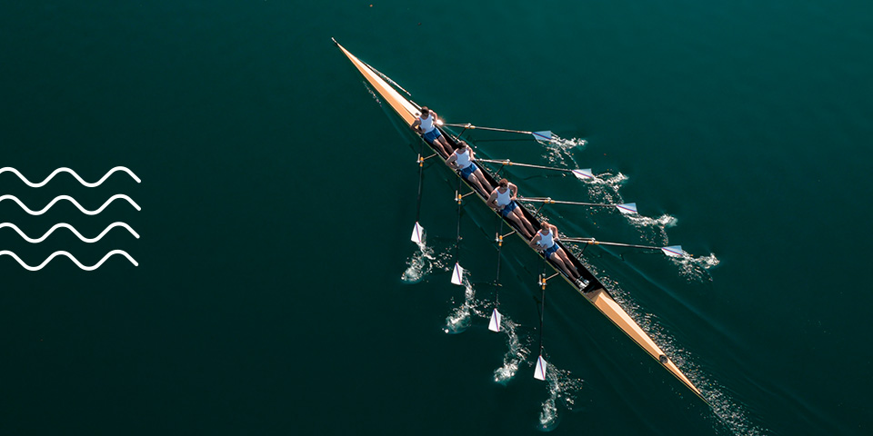 A male rowing team rows in teal water