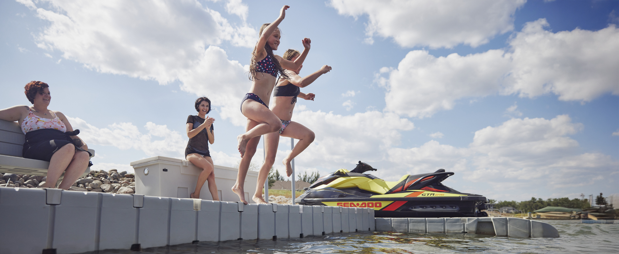kids jumping into a lake from a floating dock