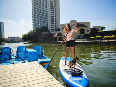 stand-up paddleboard on a lake, young lady pushing off from the dock, standing because she has the SUP skills