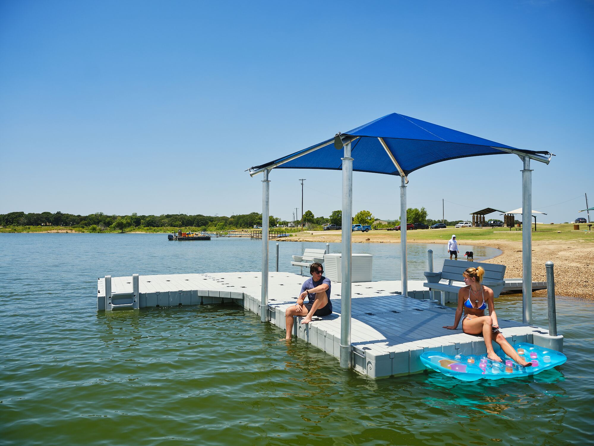 muelle flotante con una estructura de sombra azul en un entorno de parque